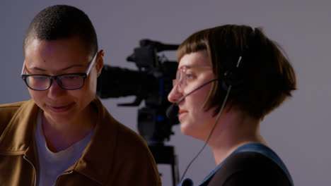 Female-Film-Director-And-Assistant-Shooting-Movie-Or-Video-Discussing-Scene-In-Studio-Shot-In-Real-Time-1